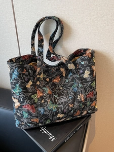 Large black jacquard tote bag with colorful butterfly patterns and fashion label