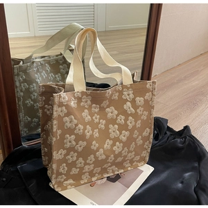 Detail view of khaki canvas tote bag featuring white floral embroidery and woven handles