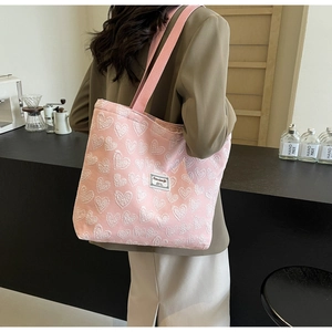 Detailed view of pink canvas tote bag with white heart texture and side label detail