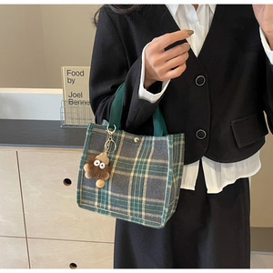 Detail of vintage plaid canvas tote bag with magnetic closure and plush doll pendant accessory