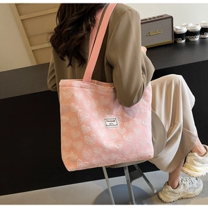 Detailed close-up of pink tote bag with white heart jacquard pattern on a stylish model