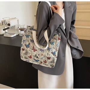 Close-up of a canvas tote bag featuring vibrant colorful butterfly prints and wide straps