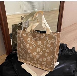 Close-up of cream canvas tote bag with white floral embroidery and reinforced handles