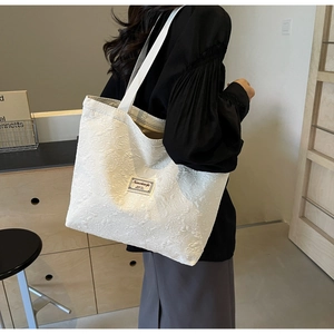 Close-up of white embossed floral jacquard tote bag with woven shoulder strap and label