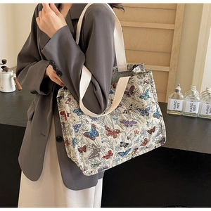 Side view of large butterfly pattern jacquard tote bag worn by a model in casual attire