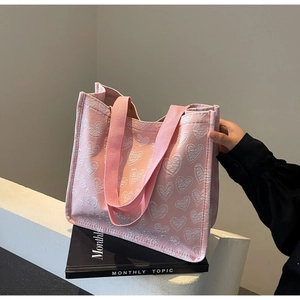 Detailed view of pink tote bag featuring white heart jacquard pattern and sturdy handles