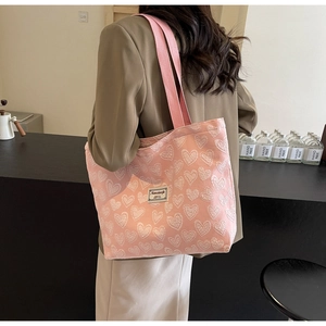 Macro view of textured pink canvas tote bag featuring 3D white heart embossed patterns