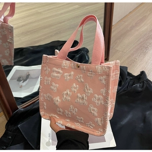Close-up of pink tote bag with white floral jacquard texture and metallic snap closure