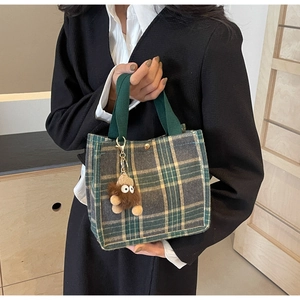 Detail of vintage plaid mini tote bag with green fabric handles and plush doll charm