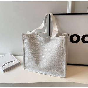 Detailed close-up of white tote bag with floral 3D embossed texture and durable woven handles