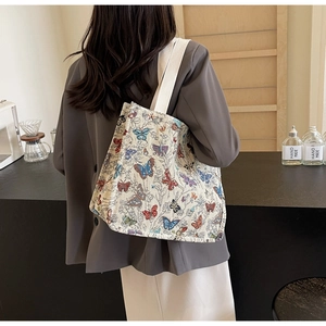 Detailed view of the large canvas tote bag featuring vibrant butterfly patterns and wide straps