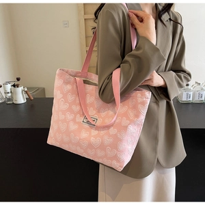 Detailed close-up of a pink canvas tote bag with heart patterns worn on the shoulder