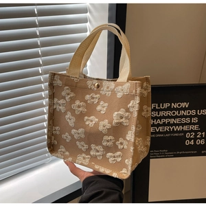 Detail of 3D floral embossed texture on khaki tote bag with a golden snap closure