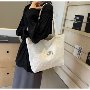 Close-up of beige canvas tote bag featuring 3D rose texture and rectangular brand label
