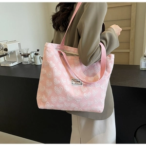 Detailed view of pink tote bag with white heart texture and secure zipper closure