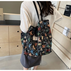 Close-up of black jacquard tote bag with colorful butterfly embroidery and logo tag