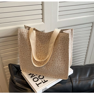 Close-up of beige tote bag with floral jacquard texture and woven straps on books