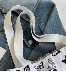 Detail of canvas tote bag with black butterfly print and thick woven shoulder strap