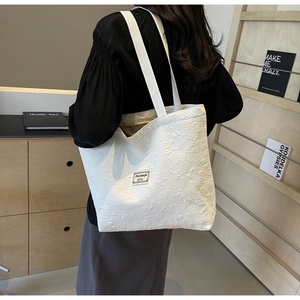 Detail of white embossed floral jacquard tote bag with textured fabric and shoulder strap