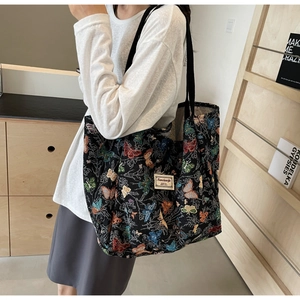 Detail of black tote bag featuring colorful butterfly jacquard and woven brand label
