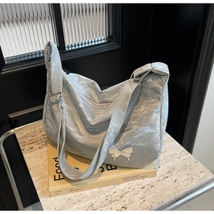 Détail du sac croissant argenté plissé avec papillon en métal et bandoulière