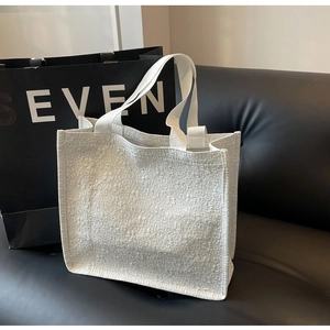 Detailed view of white tote bag with embossed floral texture on premium fabric