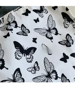 Close-up of white canvas tote fabric showing black butterfly print and twill texture