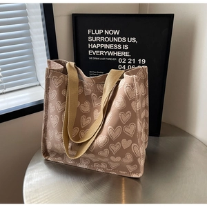 Close-up of light brown canvas tote bag with cream heart pattern on metal table