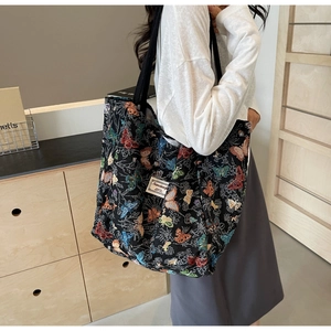 Close-up of a large canvas tote bag with colorful butterfly prints and black shoulder straps