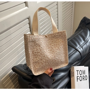 Détail du sac cabas beige à texture florale avec fermoir doré et larges anses