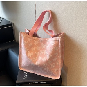 Detail of pink canvas tote bag showing white textured heart jacquard and thick handles