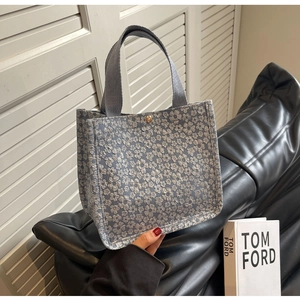 Detailed view of blue floral jacquard fabric and woven handles on a stylish tote bag