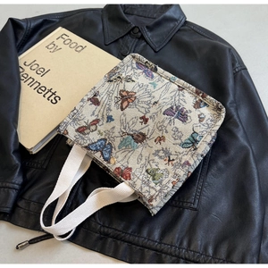 Detail of canvas tote bag showing colorful butterfly pattern and golden snap closure