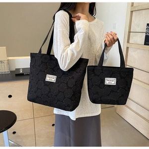 Detail of black jacquard tote bag with embossed rose pattern and white woven label