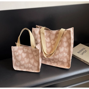 Vista dettagliata del set di due borse tote rosa con motivi a cuore e manici beige