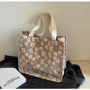 Detailed close-up of daisy embroidered canvas tote bag on vintage book and leather jacket