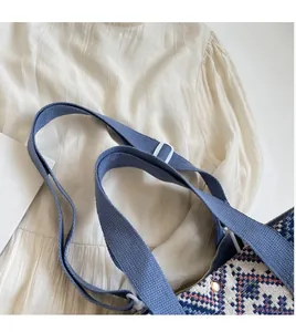 Detail of jacquard canvas bag featuring geometric patterns and blue woven shoulder strap