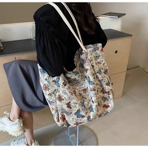 Detail of a large canvas tote bag with colorful butterfly prints and woven brand label