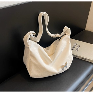 Détail du sac bandoulière blanc plissé avec boucle papillon argentée au style liquide