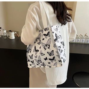 Close-up of wide canvas strap and butterfly pattern on a large white tote bag