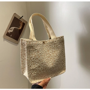 Close-up of 3D embossed floral texture and gold metal buckle on cream canvas tote bag