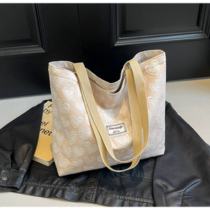 Detail of canvas tote bag featuring jacquard heart patterns and secure zipper closure