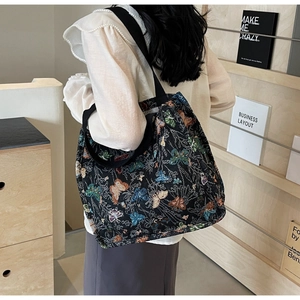 Detail of large canvas tote bag showing colorful butterfly pattern and black woven strap
