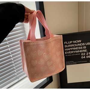 Primo piano di una borsa tote in tela rosa con cuori bianchi e trama in tessuto morbido