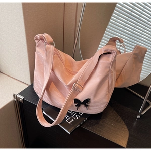 Détail du sac à bandoulière en nylon rose avec boucle papillon noire et fermeture