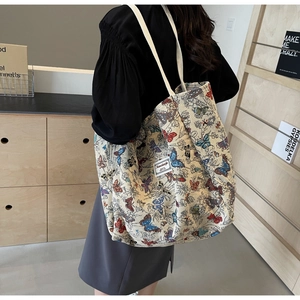 Detail of canvas tote bag with colorful butterfly print and brand label on shoulder