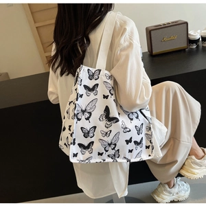 Detail shot of a white canvas tote bag with black butterfly prints in a cafe setting