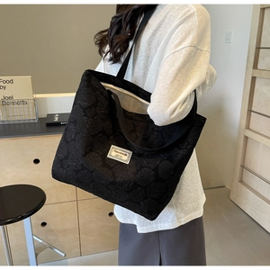 Detail of black tote bag featuring 3D rose embossed texture and minimalist brand label