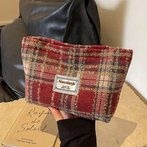 Detail of red checkered tweed makeup bag featuring a vintage fabric label and soft texture