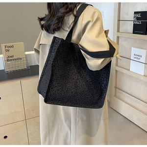 Gros plan d'un sac cabas noir en tissu jacquard texturé avec larges bandoulières